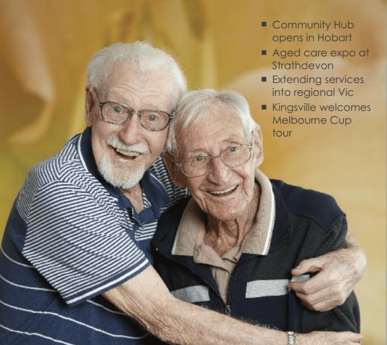 Two older adults embracing and smiling for the camera against a warm golden background. One person has an arm around the other, highlighting friendship, companionship and social connection. Text in the top-right corner lists featured stories: “Community Hub opens in Hobart”, “Aged care expo at Strathdevon”, “Extending services into regional Vic”, and “Kingsville welcomes Melbourne Cup tour”.