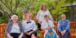 Staff and residents sitting on bench together.