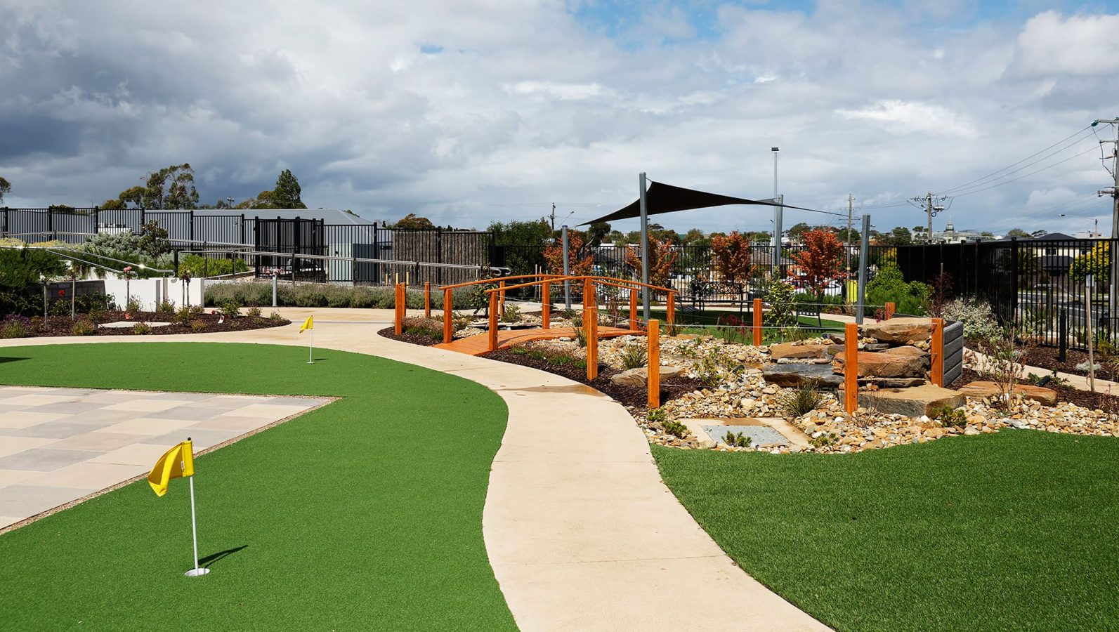 Rocky garden space with mini putting green, bridge and pergola pictured