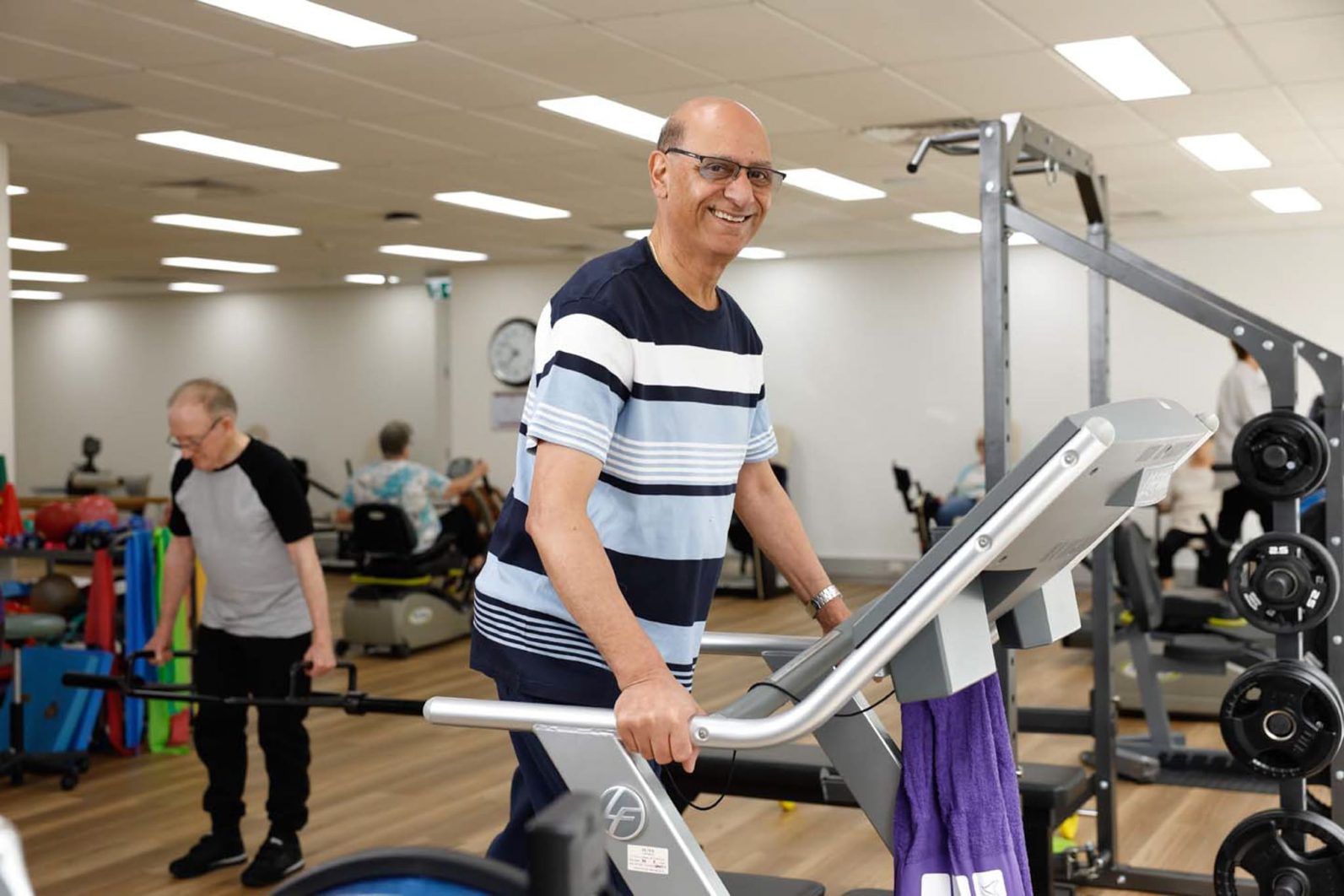 A Uniting AgeWell customer is using the gym equipment.