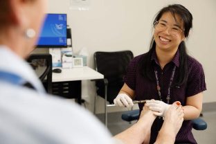 A staff member is pictured smiling while working with podiatry.