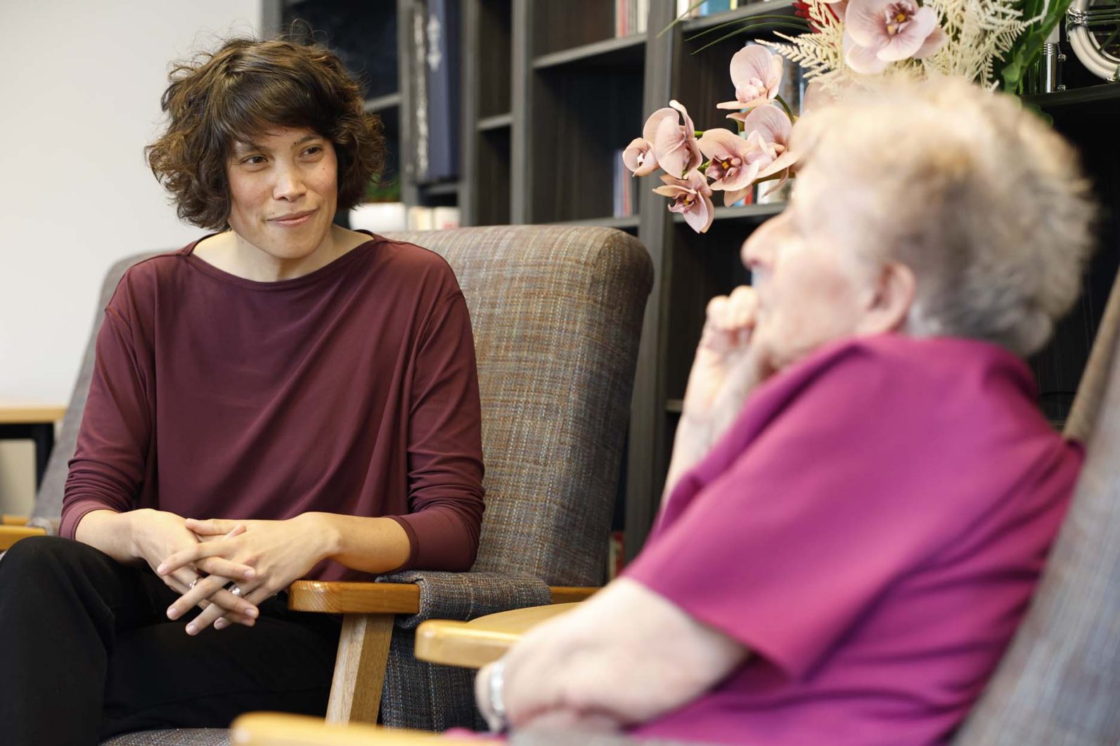 Chaplain and resident sit and talk in lounge area