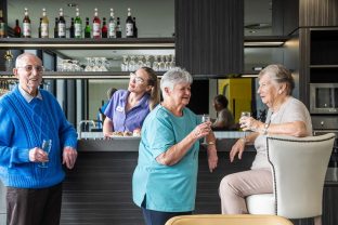 Residents talk and enjoy a drink while a staff member works behind the counter