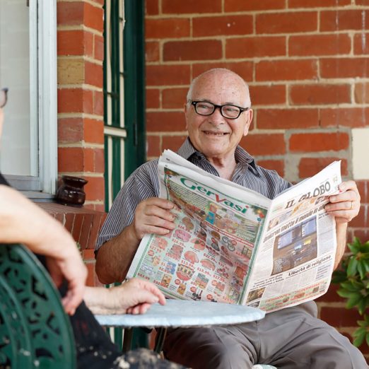 A person is pictured smiling while reading newspaper