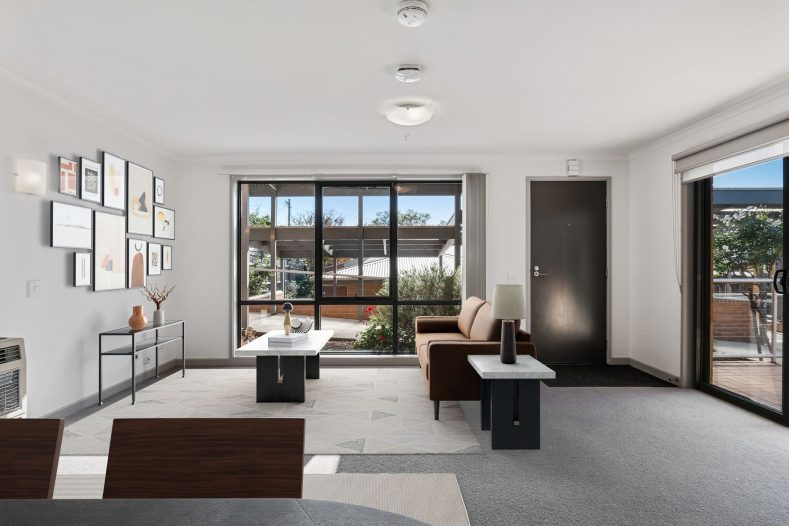 A living room is photographed with a large window on the side.