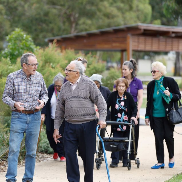 A group of social connections customers enjoying a walk and chat in a local park.
