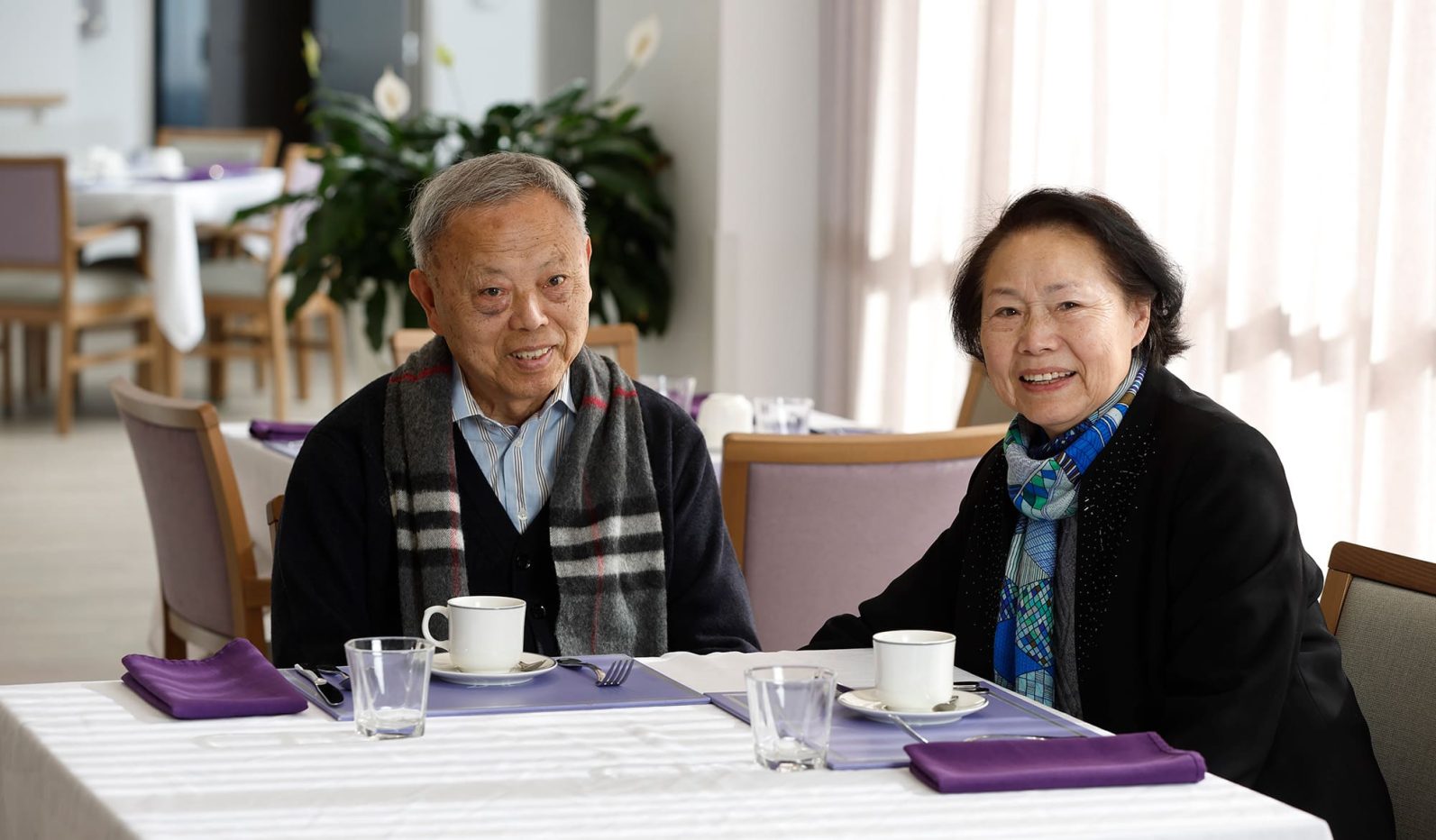 Couple sitting at dining table waiting for tea and coffee.