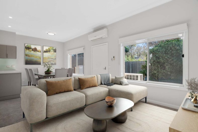 A light-filled living room is pictured with a window on the side.