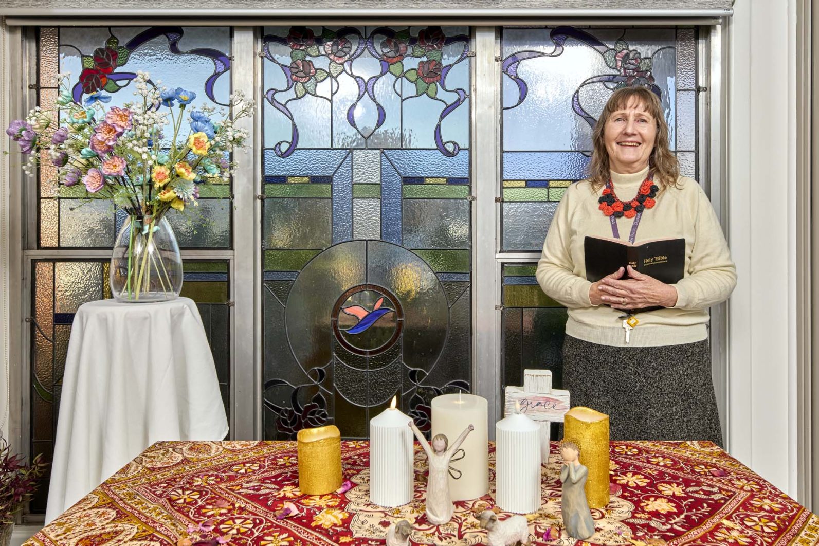 A chaplain is pictured standing in the chapel with a book in her hand.