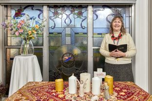 A chaplain is pictured standing in the chapel with a book in her hand.