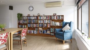 A library with huge collection of books and chair, a window is situated by the right side