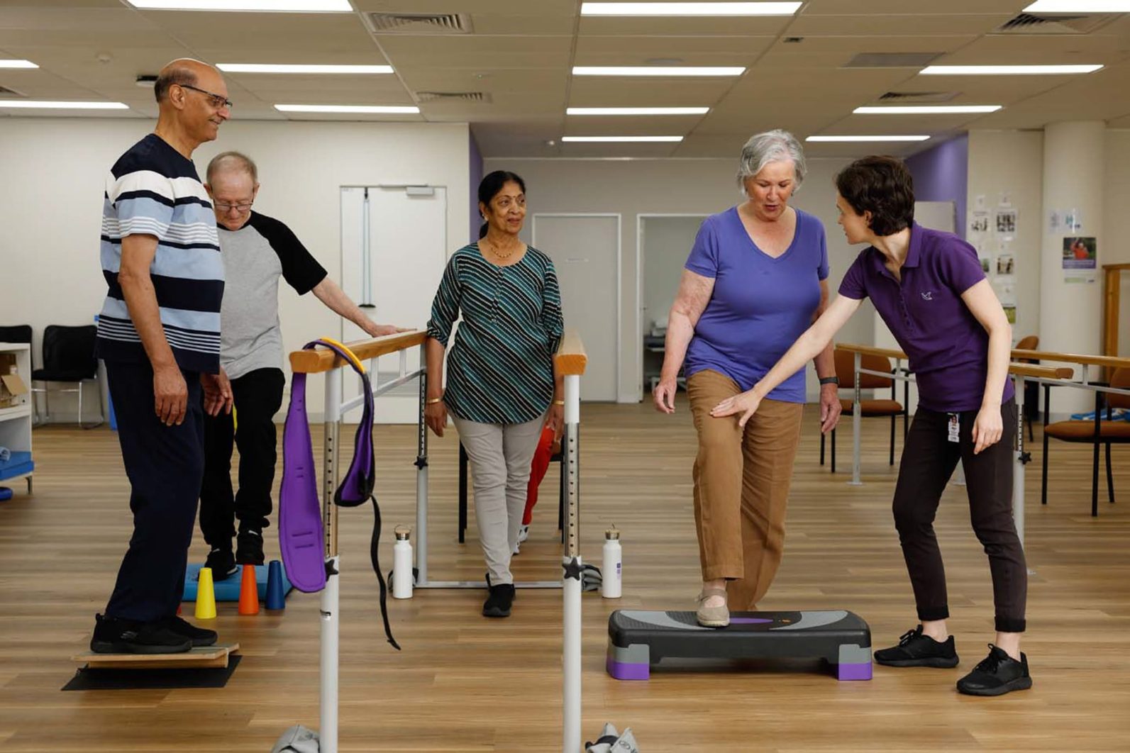 A group of Uniting AgeWell customers are pictured using the equipment with the assitance from staff member.