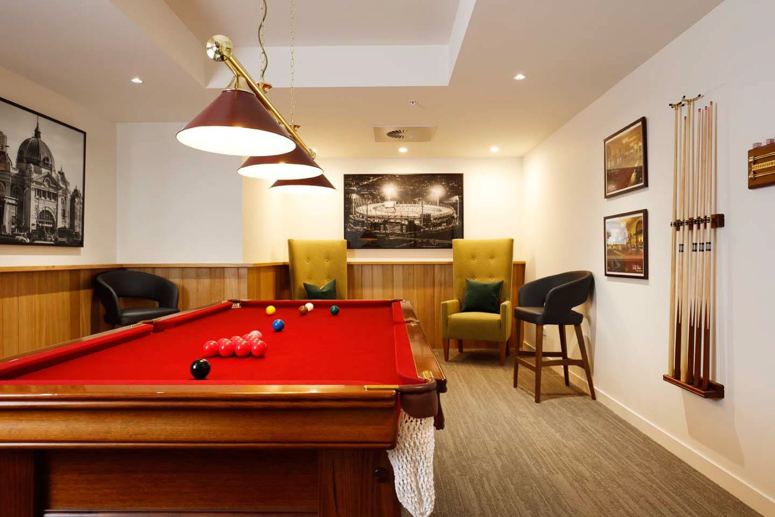 A billiards table with overhead lighting and lounge chairs is pictured.