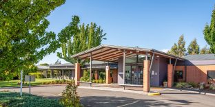 Front entry of Newnham Community, Aldersgate with driveway and trees visible.