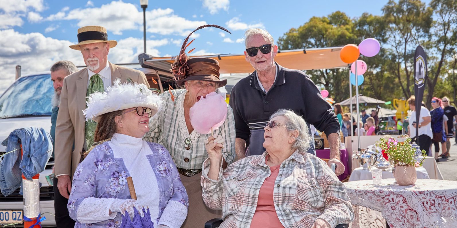 Four people smiling and enjoying fairy floss.
