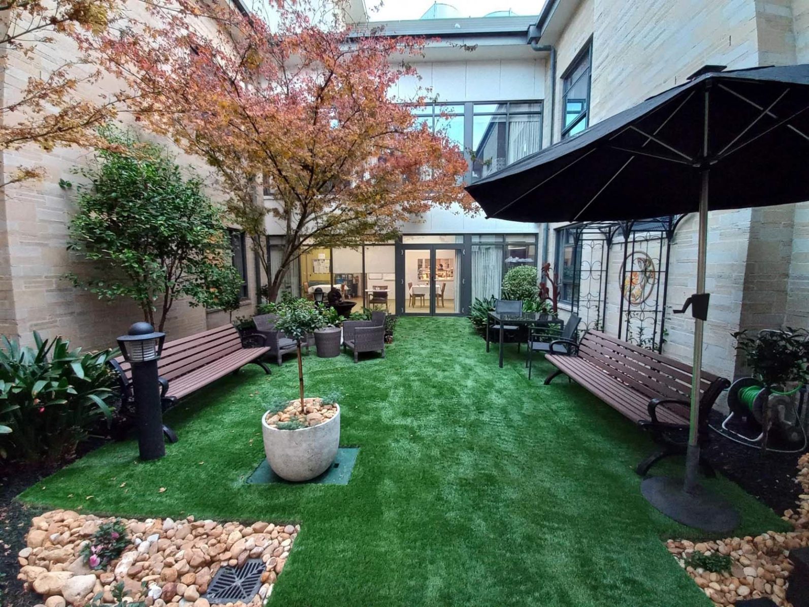 A close-up of the fountain in the garden area, behind it is the window of the community home.