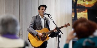 Entertainer singing and playing guitar at Preston Community.