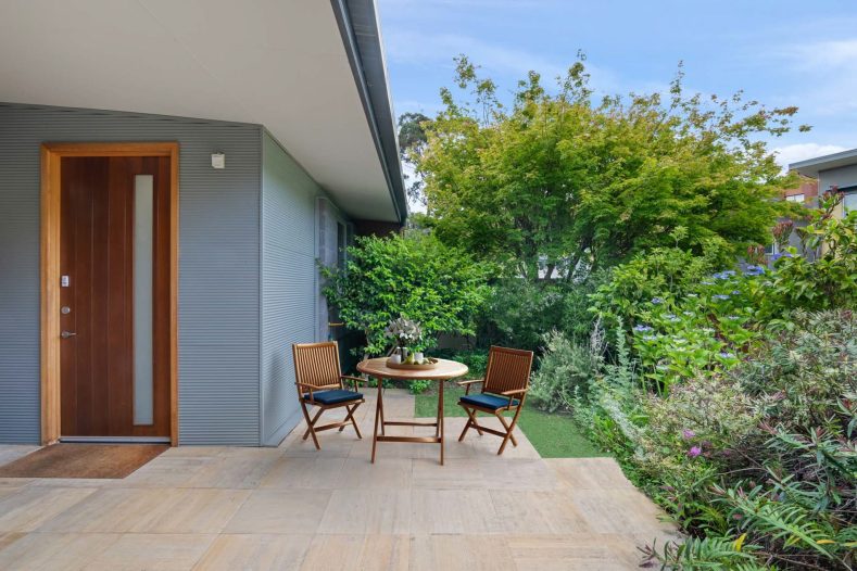 Front door area of Queenborough Rise is captured, there is a seating area next to the door.