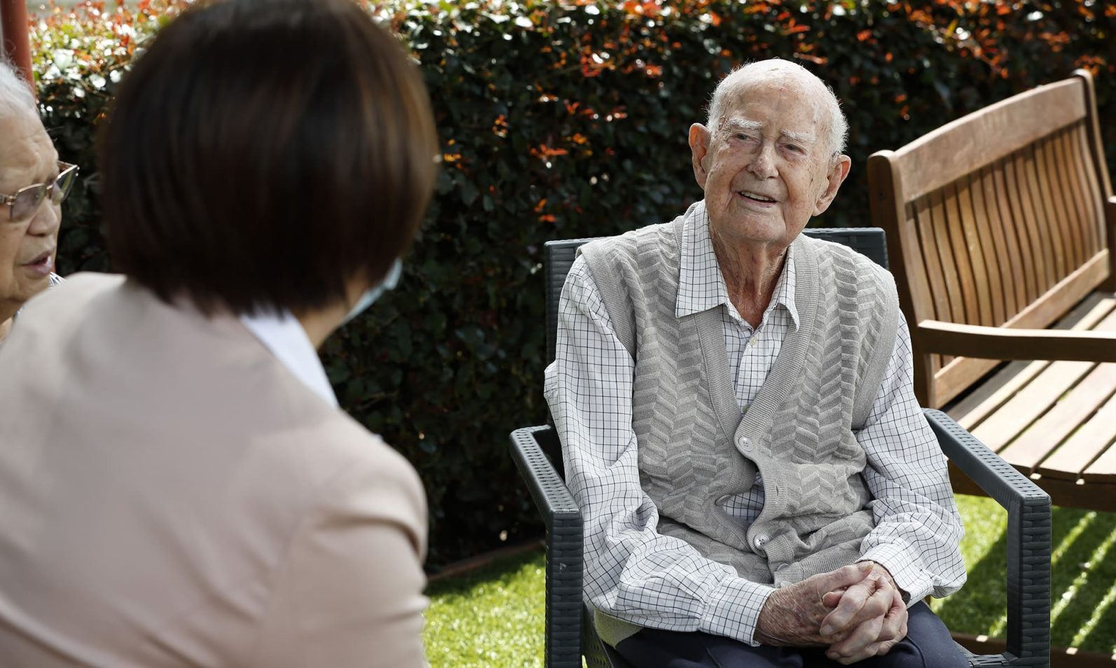 Resident and staff member sitting and talking in garden.