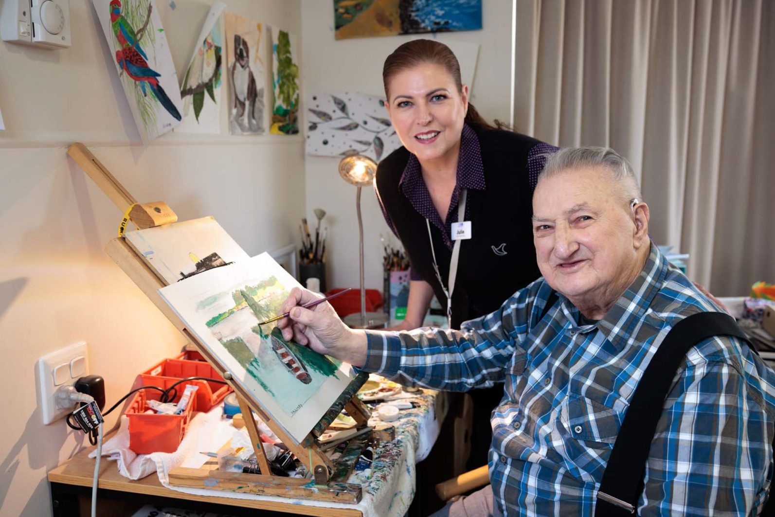 A resident and a staff member are pictured, while the resident is painting
