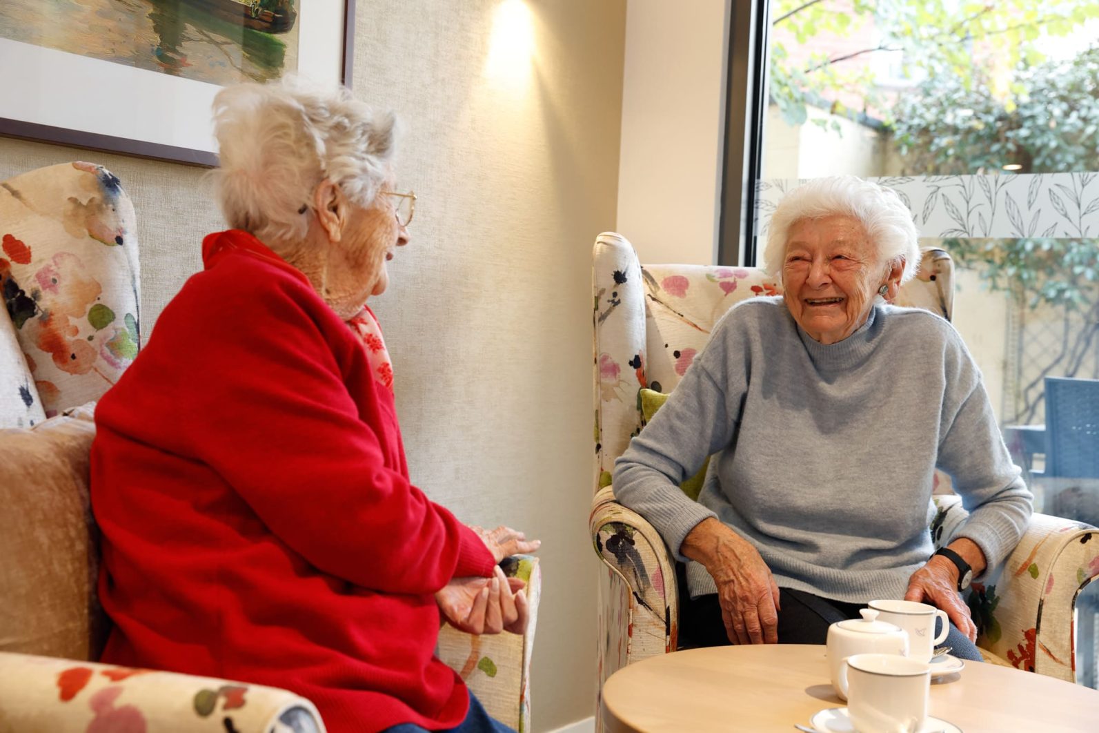 Two residents chat in the sitting area while having tea