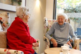 Two residents chat in the sitting area while having tea
