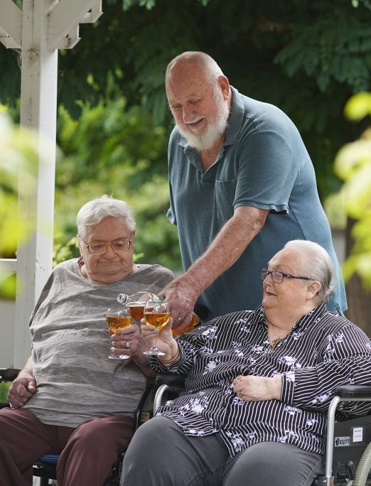Three residents having a drink together in garden.