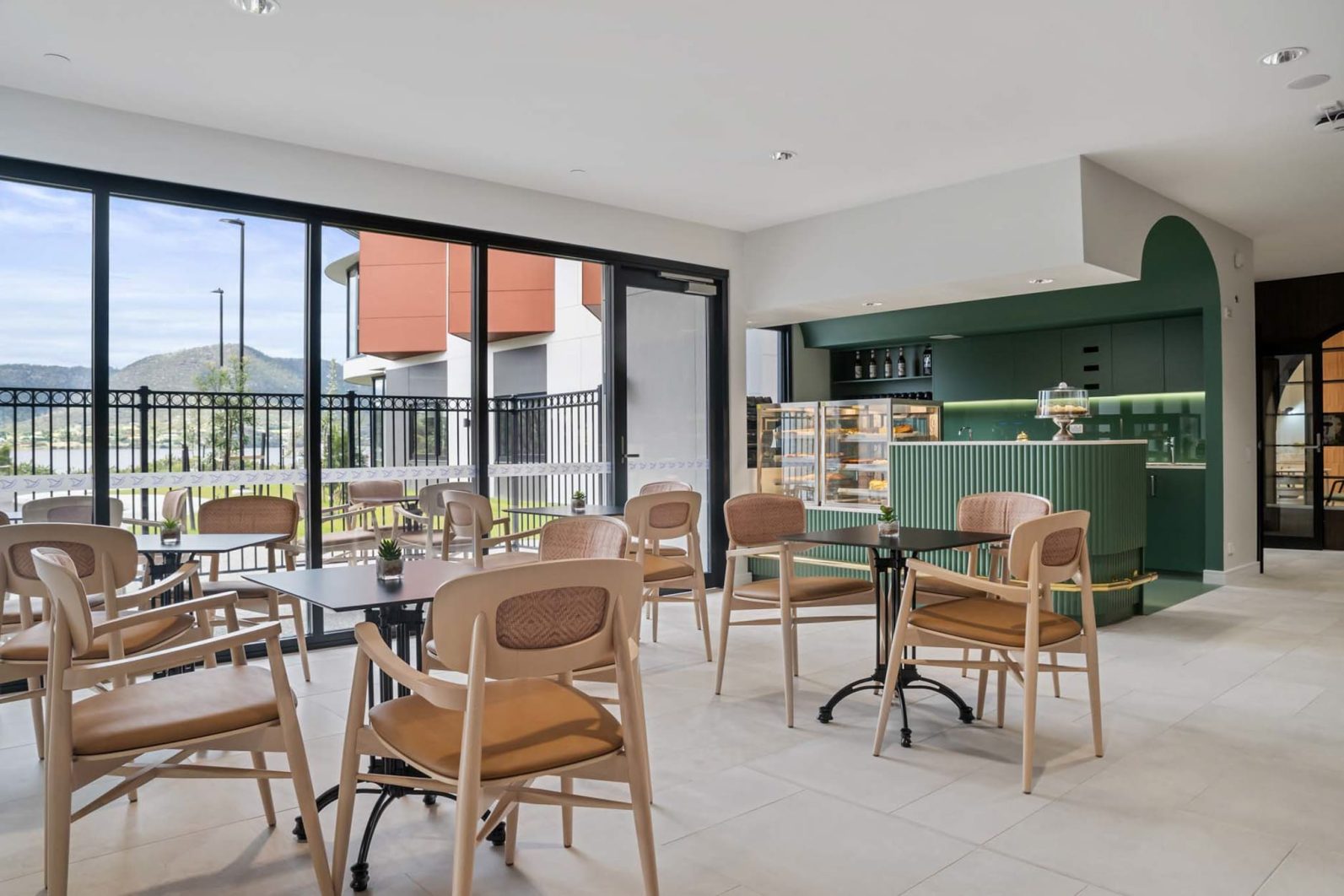 Cafe chairs and tables facing a lovely outdoor view and a green cafe setup is pictured.