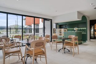 Cafe chairs and tables facing a lovely outdoor view and a green cafe setup is pictured.