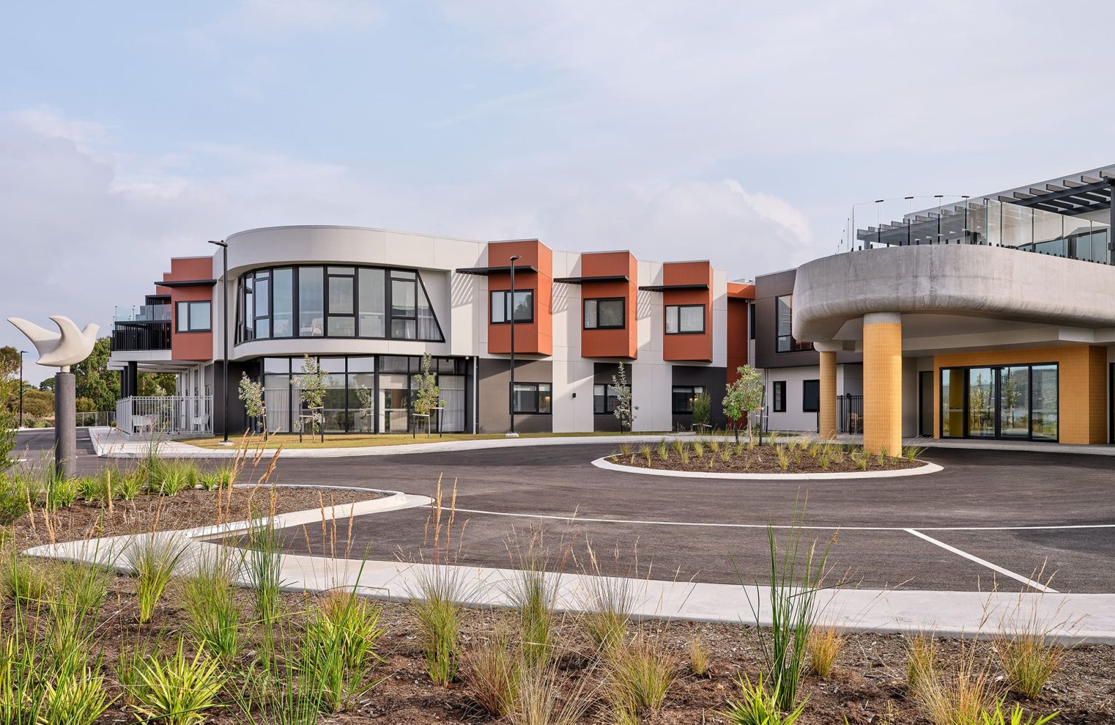 The main entrance of Rosetta Community, Strathaven Waterfront Wing is photographed, where the main building and parking area are in sight.