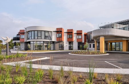 The main entrance of Rosetta Community, Strathaven Waterfront Wing is photographed, where the main building and parking area are in sight.