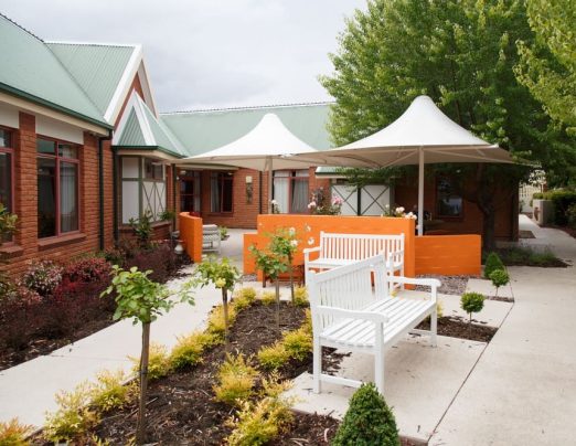 Outdoor courtyard with white umbrellas and white bench seating.