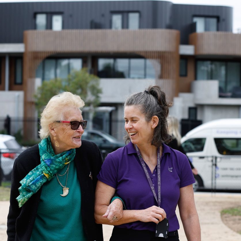 Social connections customer and carer are pictured holding hands on a walk.