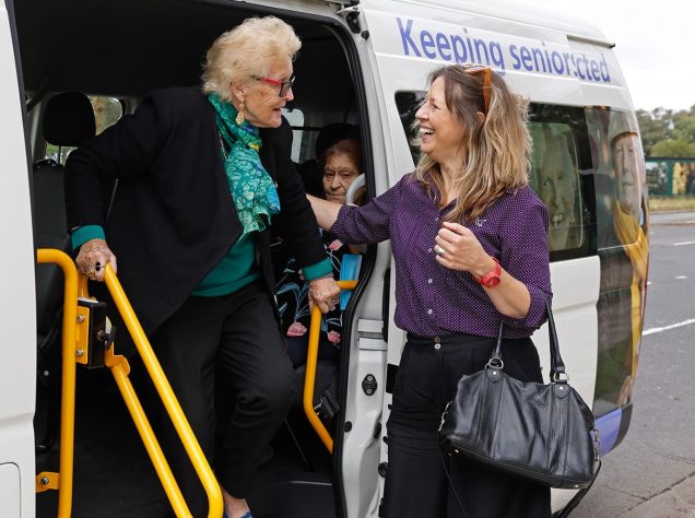 Uniting AgeWell staff member is pictured helping a customer disembarking a vehicle.