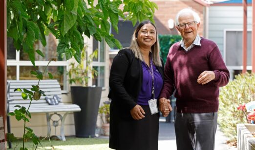 Staff member and resident standing in garden.