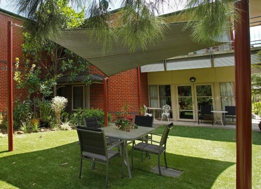 Outdoor table and chairs under shade cloth.