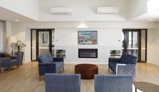 A lounge room with fireplace and colourful painting in the centre