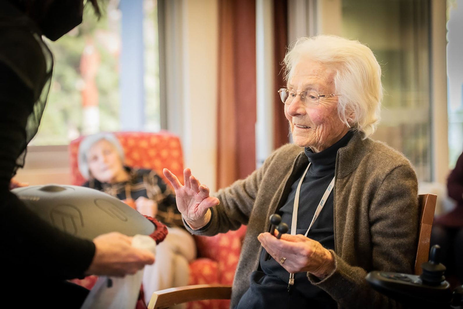 A resident uses a handpan held by a member of the TSO.