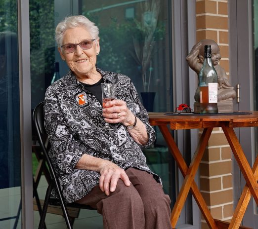 Resident enjoying glass of wine seated on their balcony.