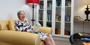 Resident sitting on lounge in library.