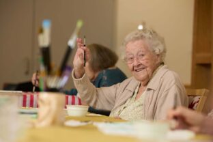 A resident waves at the camera while painting.