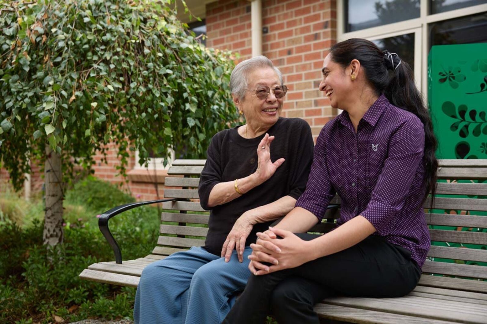 A resident and a personal care worker chatting in the garden.