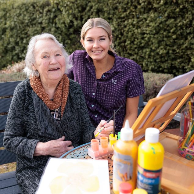 Customer and staff member are painting in the garden