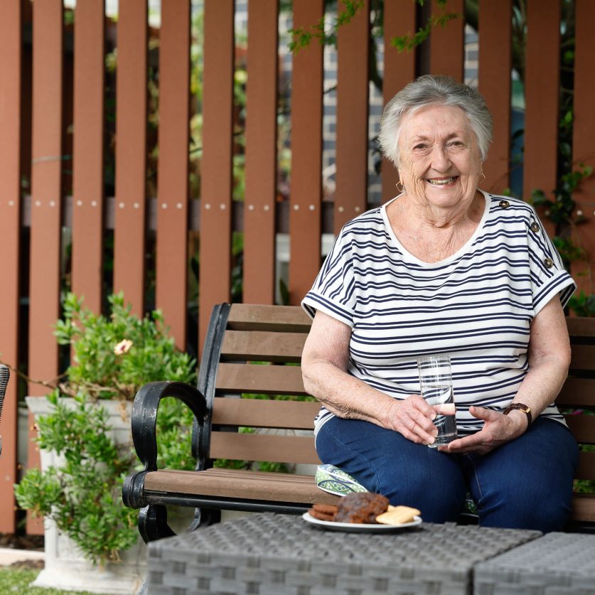 A person sitting on a bench is smiling at the camera