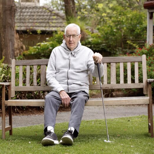 Person sitting on bench holding golf club.