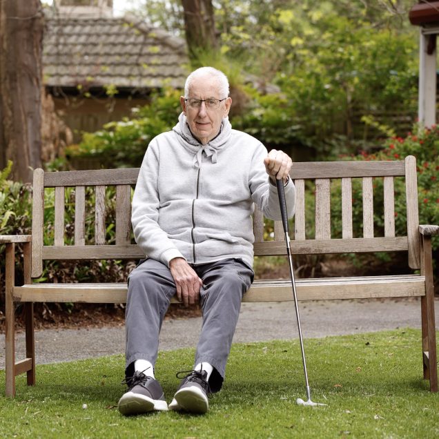 Person sitting on bench holding golf club.