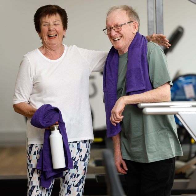 The AgeWell Gym customers are pictured laughing together and they hold towels from Uniting AgeWell.