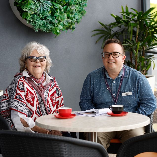 Chaplain and resident sitting at table together.