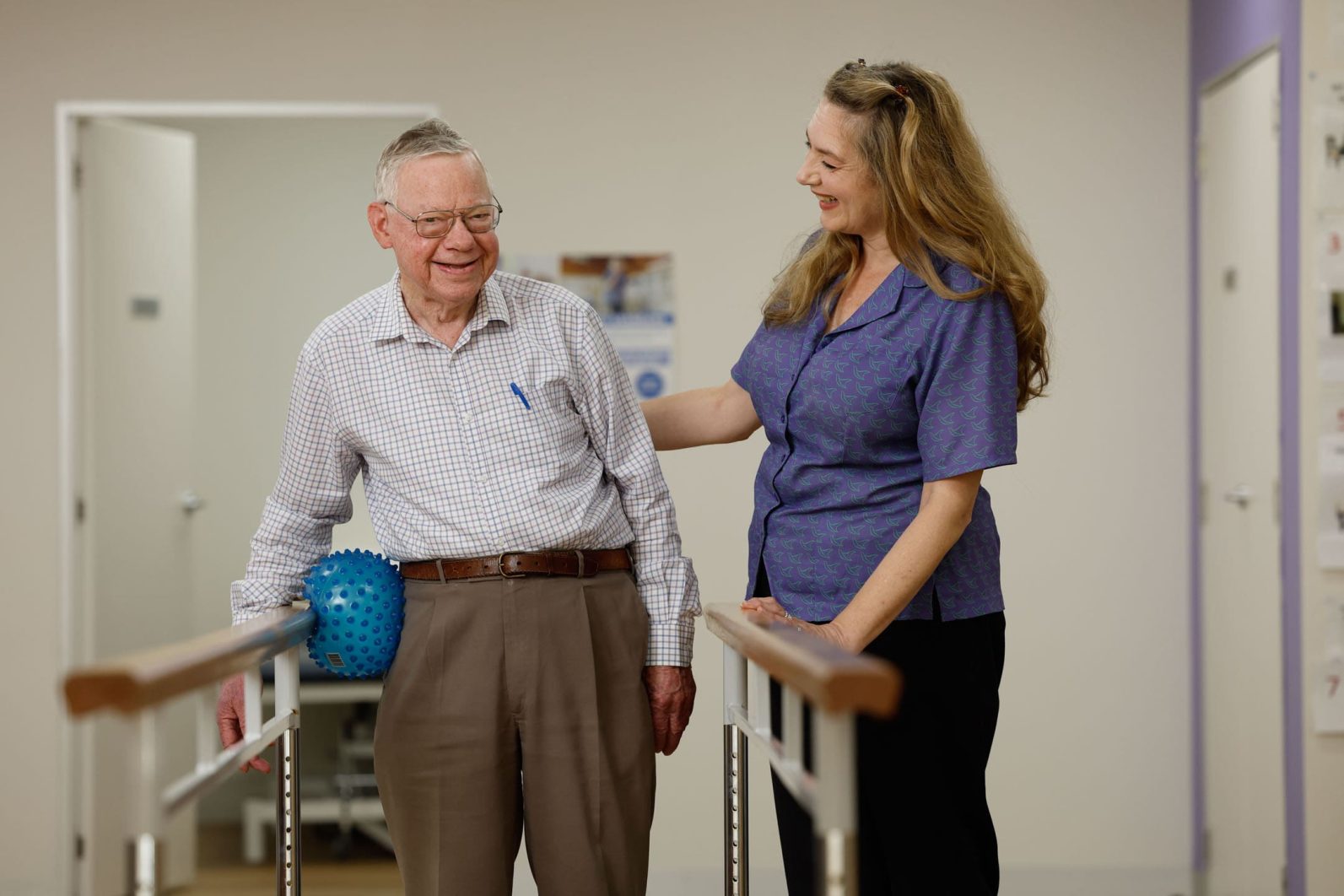 Customer with staff member completing wellness exercises in gym.