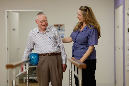 Customer with staff member completing wellness exercises in gym.